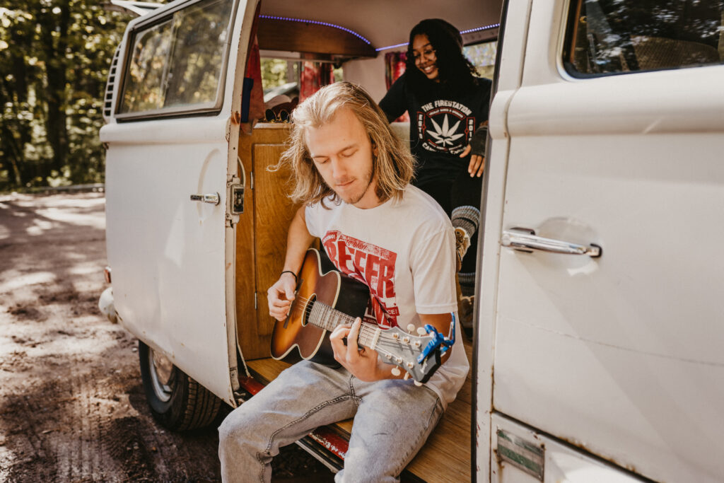 A young man playing a guitar in a VW van with friends in Marquette, Michigan.